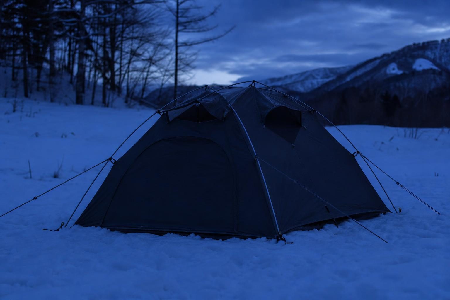 冬の夜のキャンプ場。換気口（ベンチレーター）を開けたテントの外観。テントの中にも周りにも暖房器具・火器は置かない