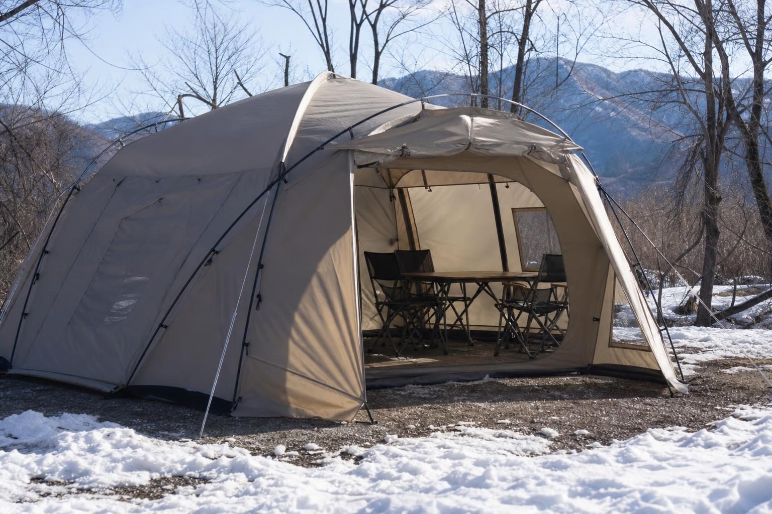 雪の残る冬のキャンプ場に張られた大きな2ルームテント。リビングにテーブルと椅子