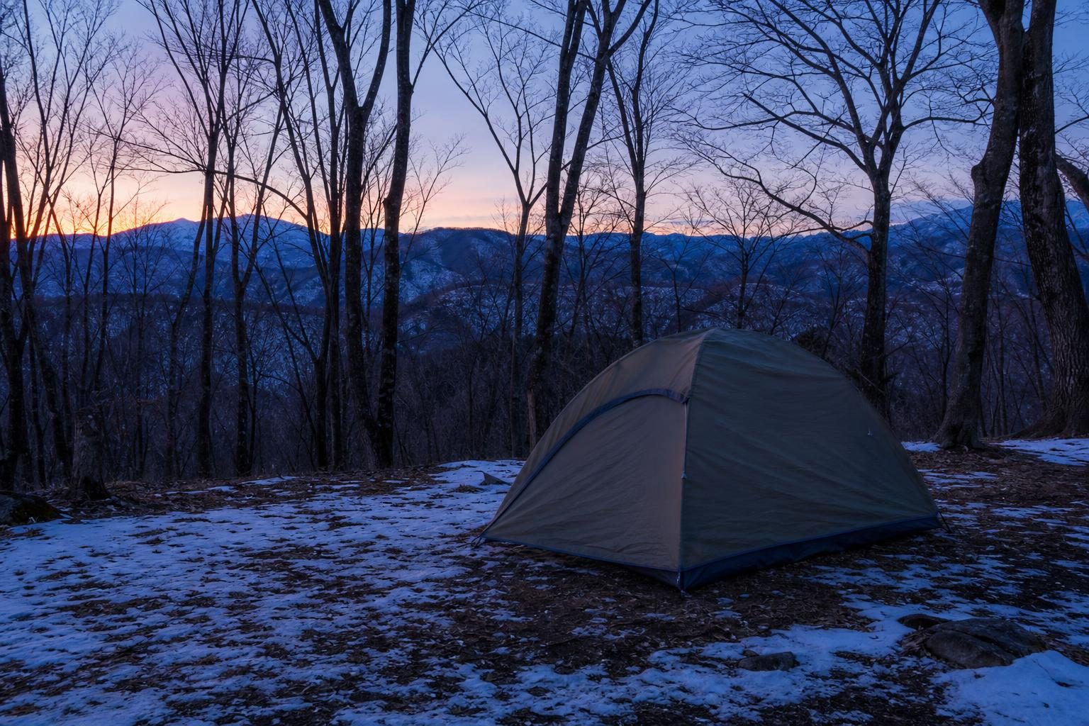 冬の夕方、雪の残る地面に張られた入口を閉じたドーム型テントの外観