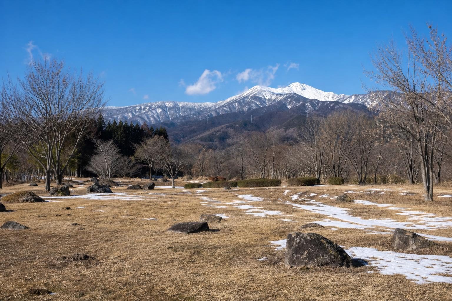 冬の晴れた日中、雪の少し残る広いキャンプ場の遠景